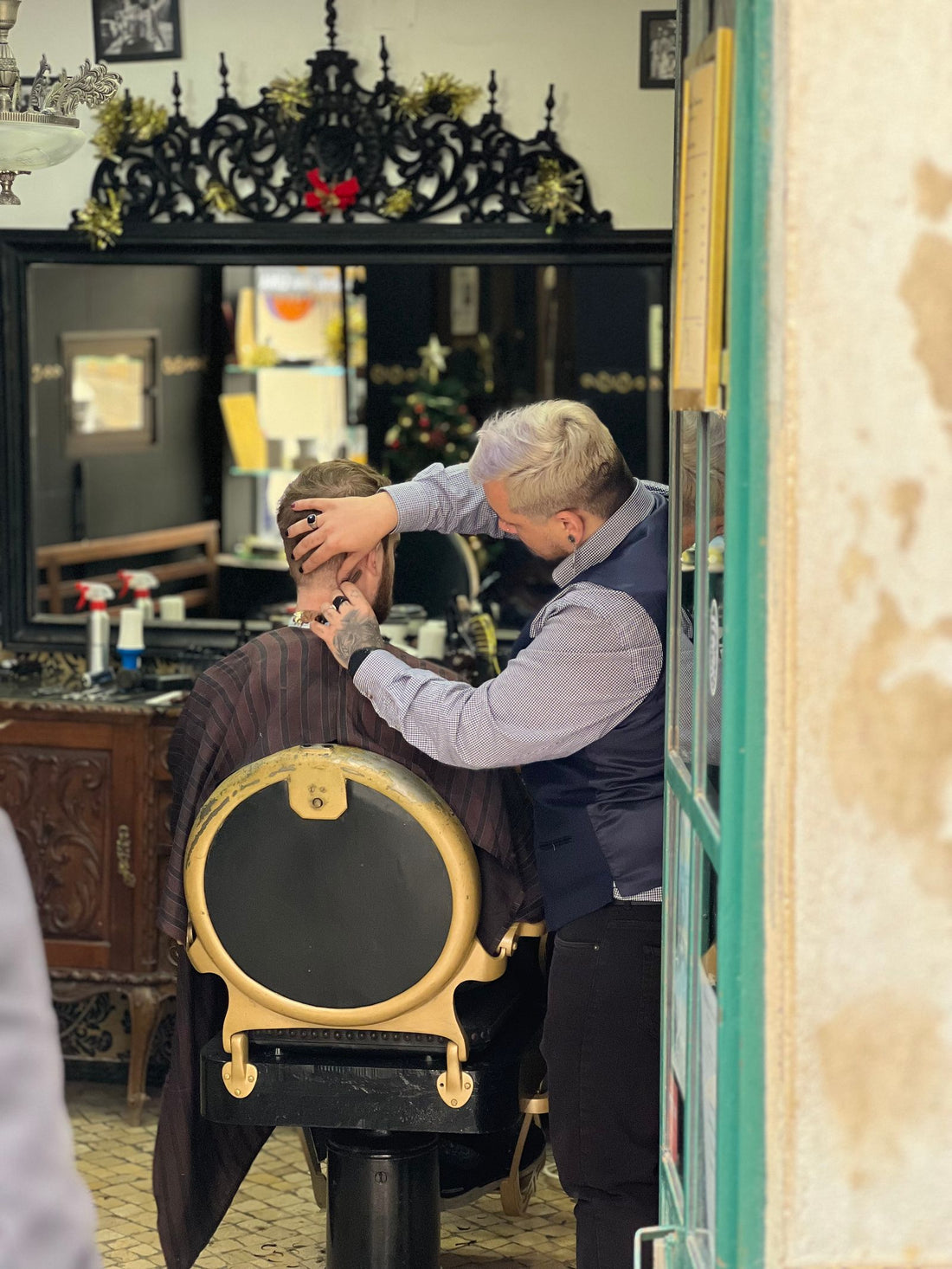 An elderly barber cutting a client's hair