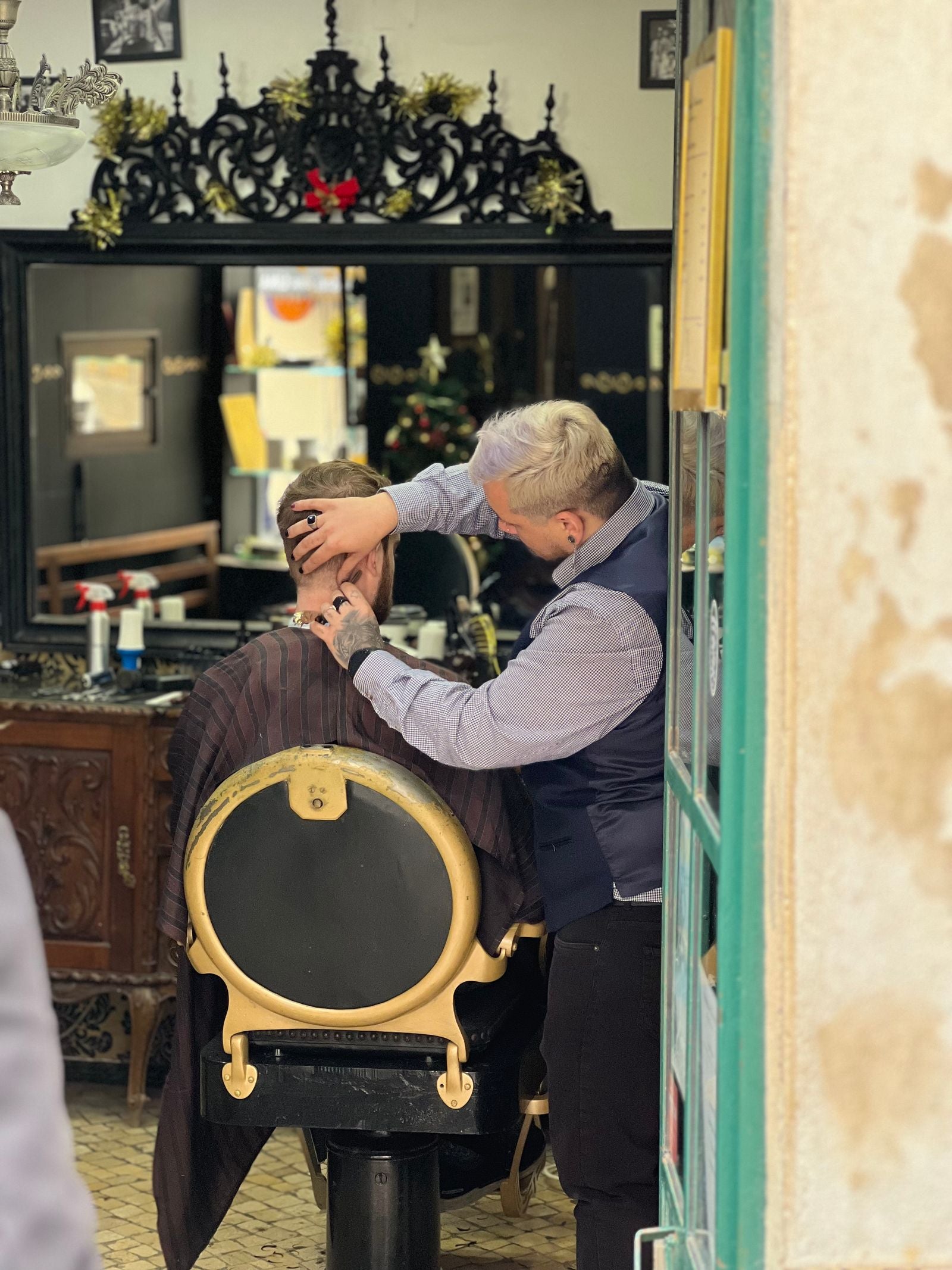 An elderly barber cutting a client's hair