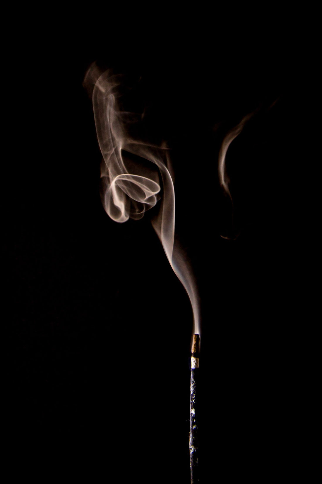 Incense smoke rising against a black background