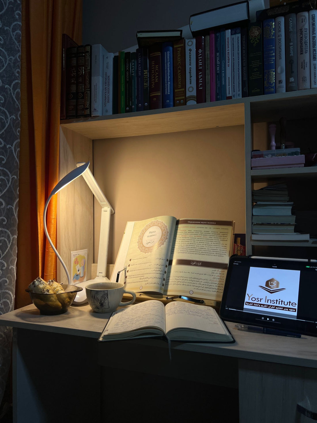 A desk with books and a screen at night