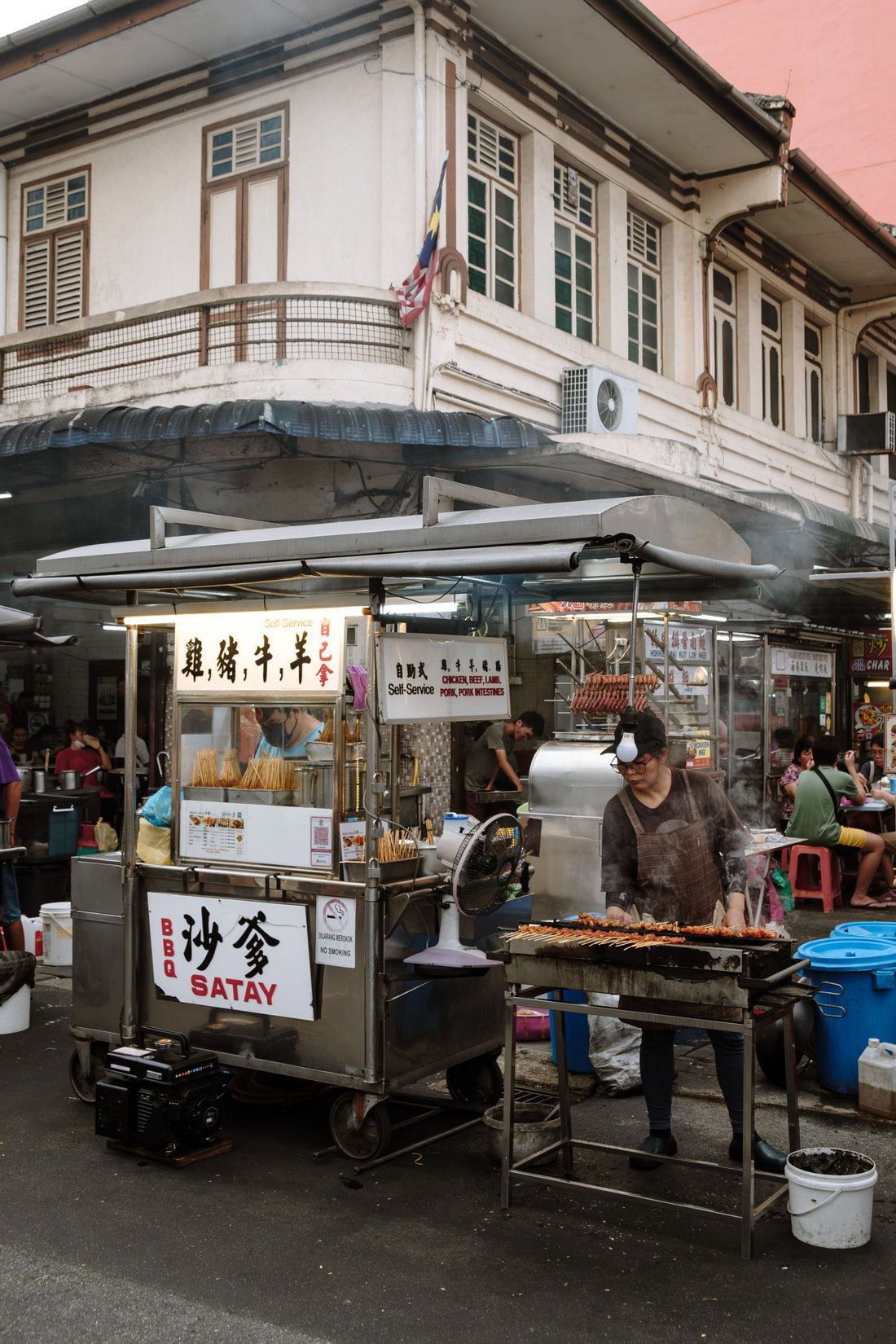 A street vendor grilling satay over charcoal