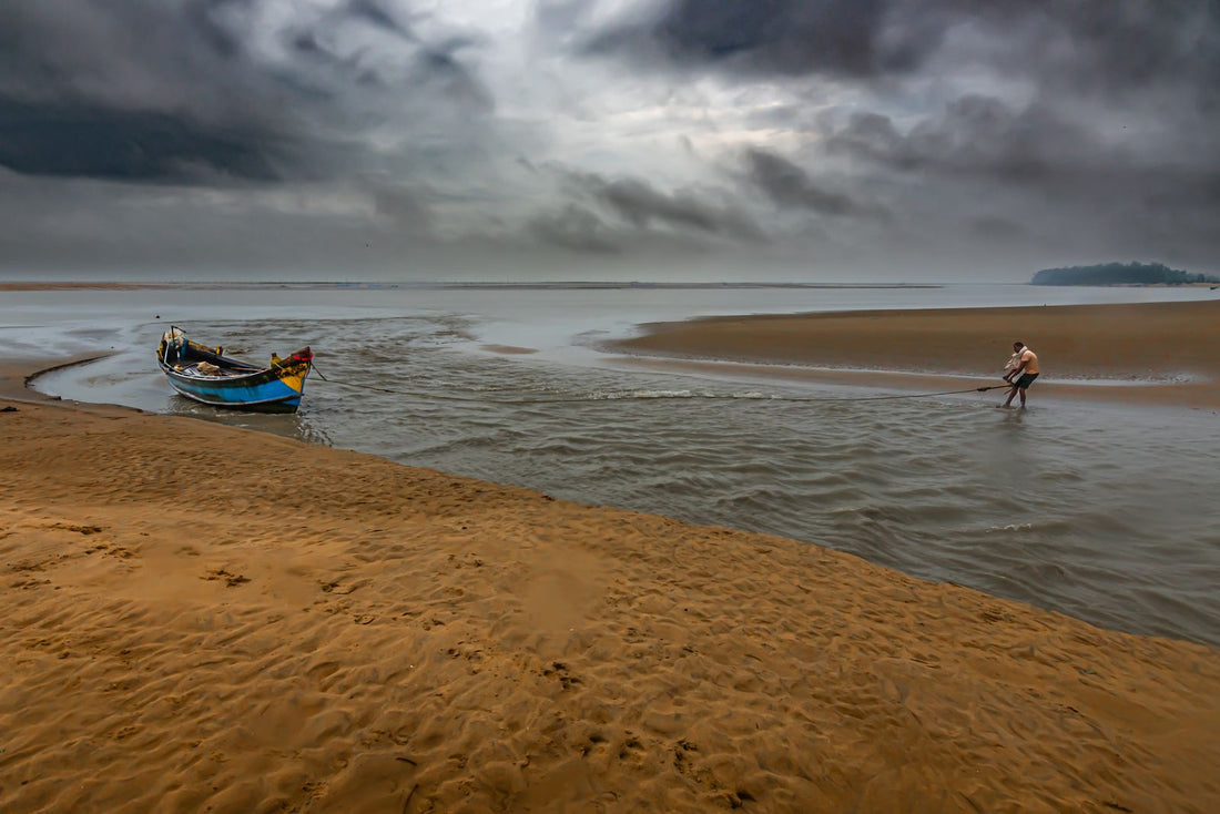 A fisherman on the coast under monsoon clouds