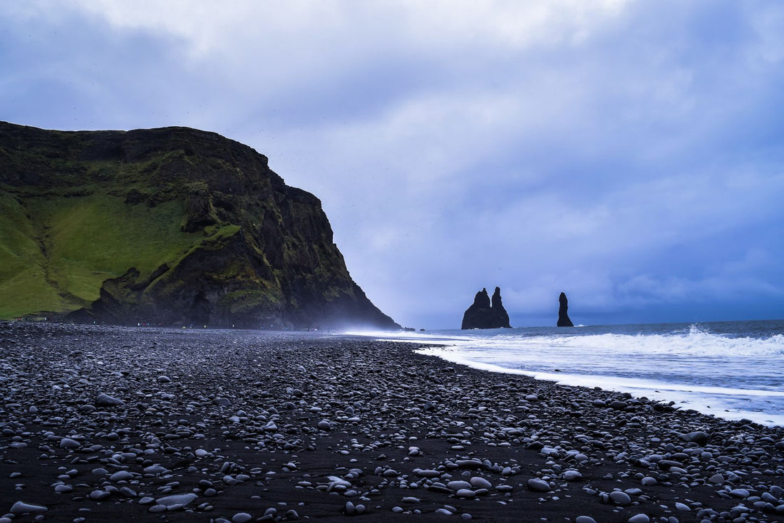 Black sand beach and basalt sea stacks under a grey northern sky